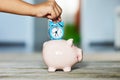 Save time concept with childÃ¢â¬â¢s hand holding alarm clock over a ceramic piggy bank